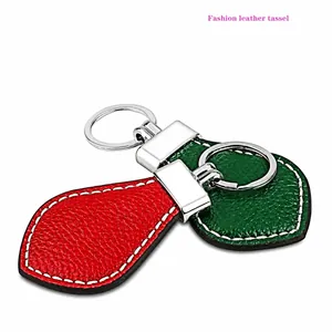 Close-up of leaf-shaped leather keychains in red and green with white stitching and silver ring