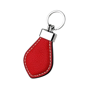 Close-up of red lychee pattern leather car keychain with white stitching and silver ring