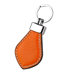 Detail of orange lychee grain leather keychain with white stitching and silver hardware