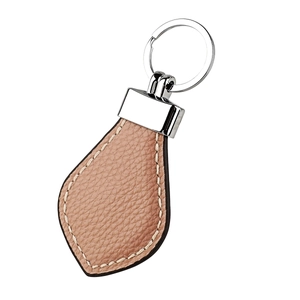 Macro shot of light brown pebble leather keychain with white stitching and silver metal ring