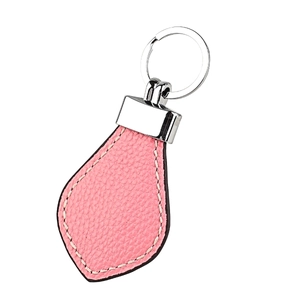 Detailed view of pink leather teardrop keychain with white stitching and silver hardware