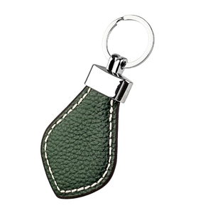 Detail of dark green pebbled leather keychain with white contrast stitching and silver ring