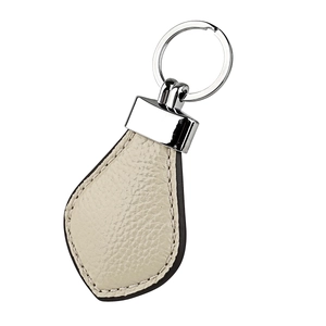 Close-up of cream leather car keychain with lychee texture and silver metal ring