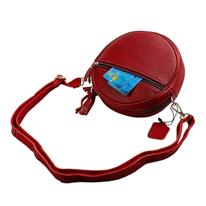 Detailed view of red round leather crossbody bag with tassel and card slot storage
