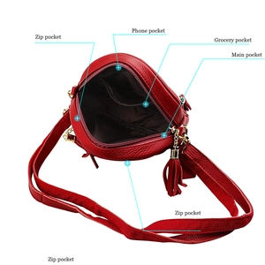 Detail view of red leather crossbody bag showing inner compartments and tassel zipper