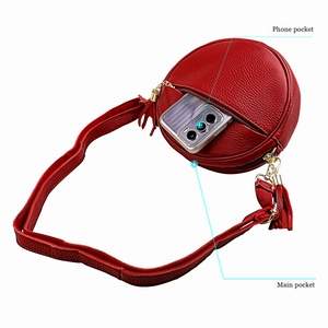 Detail view of red leather crossbody bag showing functional phone and main pockets