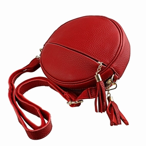 Detail of red circular leather crossbody bag with lychee grain texture and tassels
