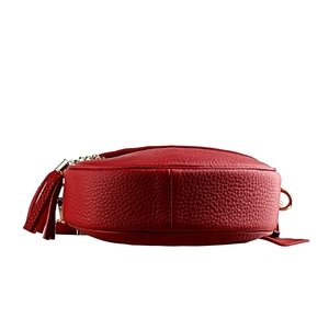 Detail view of red pebble leather bag with gold hardware and stylish tassel charm