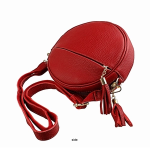 Side view of red pebble leather round crossbody bag with tassels and gold hardware