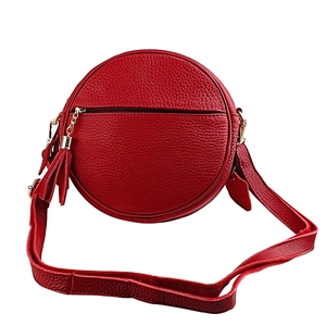 Detail of red pebbled leather round crossbody bag with zipper and tassel accent