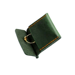 Dettaglio della borsa porta gioielli in pelle verde scuro con cuciture arancioni