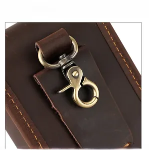 Macro detail of crazy horse leather stitching and vintage brass metal hook on belt pouch