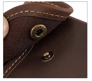 Macro detail of star embossed bronze snap button and stitching on brown leather pouch