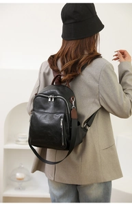 Rückansicht einer Frau mit schwarzem Kunstleder Rucksack und silbernen Reißverschlüssen