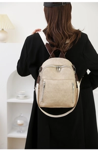 Modischer Rucksack aus cremefarbenem Leder mit braunen Riemen, von einem Model getragen