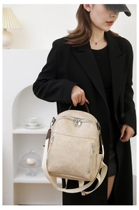 Nahaufnahme eines beigen Lederrucksacks mit braunen Griffen und Metallreißverschlüssen