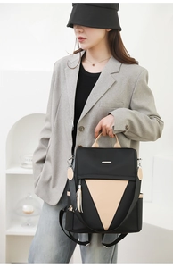 Detailed view of a nylon travel backpack with beige V-shaped panel and side tassel detail