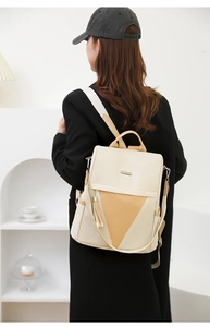 Detail of a minimalist beige PU leather backpack with a brown triangle stitch and tassel charm