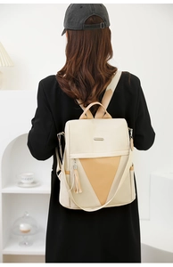 Detail of two-tone nylon travel backpack with tassels and side pockets on female model