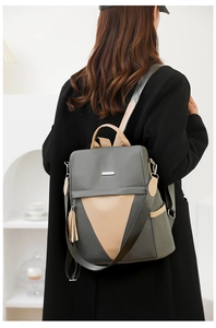 Detailed back view of a grey-green nylon travel backpack with stylish tassel charm