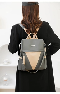Detail of grey and beige nylon backpack showing contrast panel and tassel decor on back