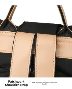 Detail of reinforced shoulder strap stitching on a bicolor nylon and leather travel bag