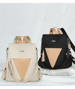 Detail of nylon backpacks in beige and black with contrast triangle stitching and tassels