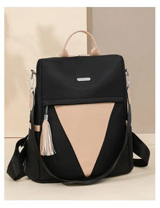 Detail of black nylon backpack featuring khaki triangle contrast and tassel charm