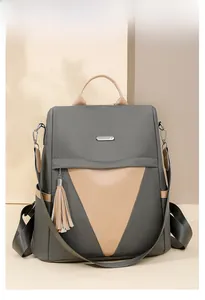 Close-up of two-tone nylon backpack with leather tassel detail on geometric background