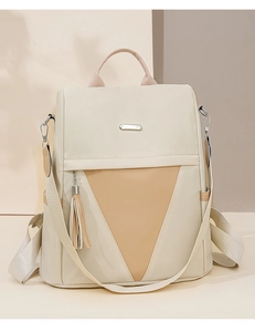 Close-up of beige nylon backpack featuring a color-block triangle design and tassel charm
