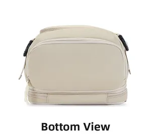 Detail of beige nylon backpack showing bottom zippered compartment and side buckle