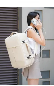 Detail view of cream travel backpack showing USB port and side compression buckle strap