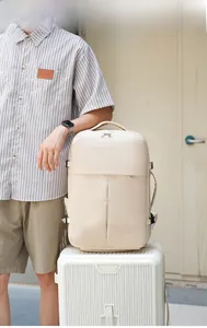 Beige travel backpack with USB port and shoe compartment mounted on a white suitcase