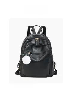 Detail view of black PU leather backpack with gold zippers and white plush ball charm