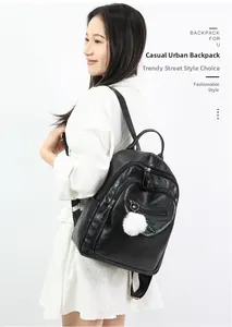Detail of black faux leather backpack with multiple zipper compartments and white pompom charm