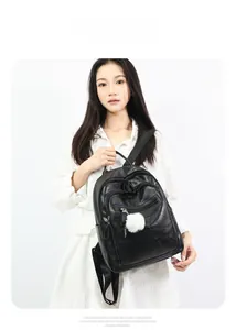 Detail of black soft leather backpack for women featuring a white pompom and zippers
