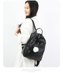 Fashionable black faux leather backpack with white faux fur pompom and leaf zipper detail