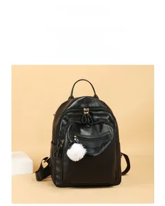 Detail view of black faux leather backpack featuring a cute decorative fur ball charm