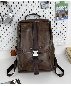 Detail of dark brown vintage PU leather backpack featuring metal buckles and plush bear charm