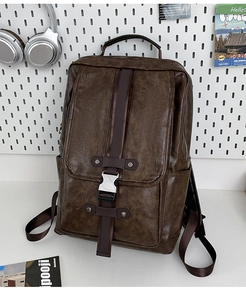 Detail of vintage dark brown PU leather backpack with metal buckle on a white desk