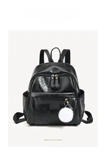 Close-up of black PU leather backpack featuring metal zippers and white fluffy pom pom charm