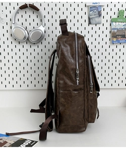 Detail of vintage brown PU leather backpack showing lychee texture and silver side zippers