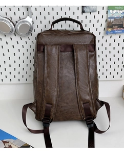 Detail view of the brown PU leather backpack rear showing padded straps and side pockets