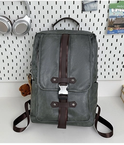 Detail of dark gray matte leather backpack featuring brown straps and silver metal buckles