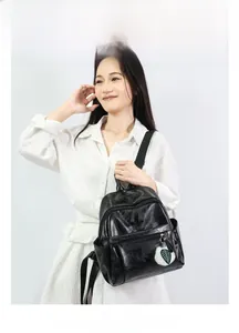 Litchi texture black PU leather backpack detail with golden zippers and white pom-pom charm