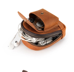 Macro detail of vintage leather pouch showing coins, keys, and earphone storage capacity