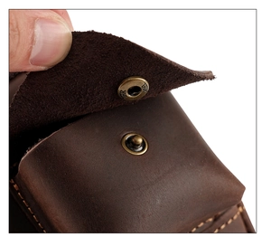 Macro shot of YKK bronze metal snap button on dark brown leather outdoor waist bag pouch
