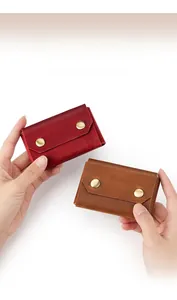 Hand holding compact crazy horse leather card holder in burgundy and brown finish