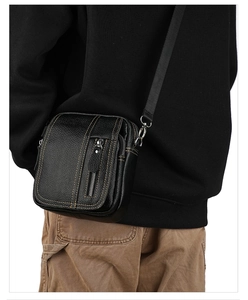 Detail of black pebbled leather crossbody bag with yellow contrast stitching and zippers