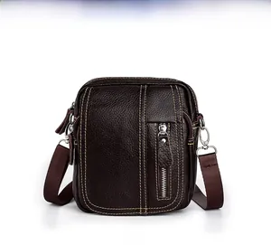 Detail view of brown leather crossbody bag with lychee texture and silver metal buckle
